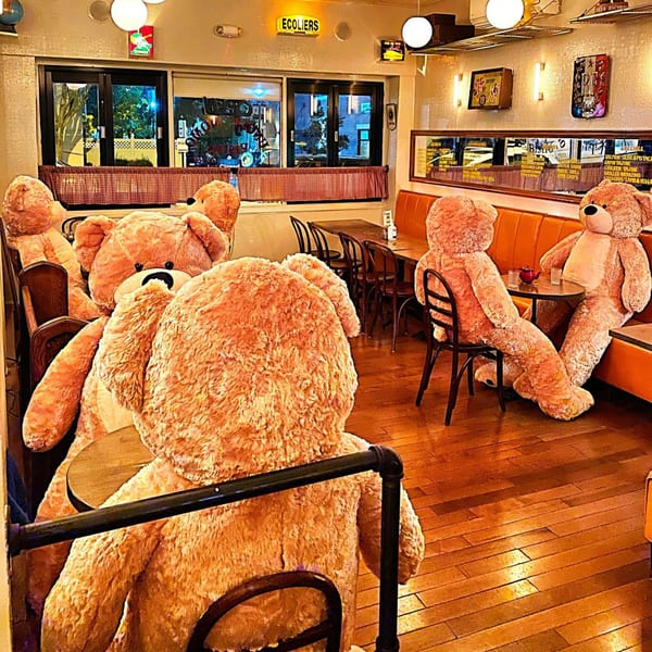 Giant teddy bears sit at tables and booths in a cozy Lebanese restaurant dining room.
