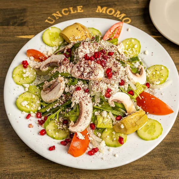 Lebanese salad with cucumbers, tomatoes, mushrooms, feta, pomegranate seeds, and artichoke hearts.