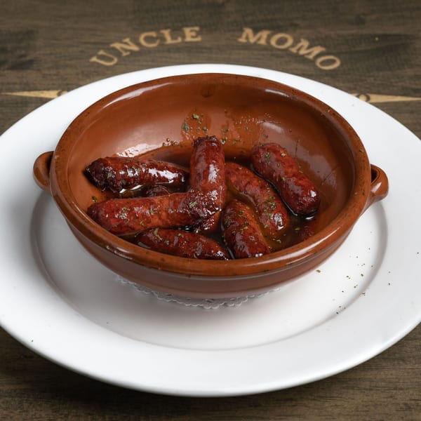 Uncle Momo's Lebanese sujuk sausages in a brown ceramic dish on a white plate.