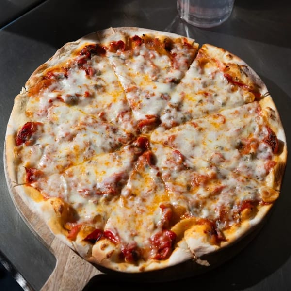 A freshly baked, sliced pizza with melted cheese and red sauce on a wooden board.